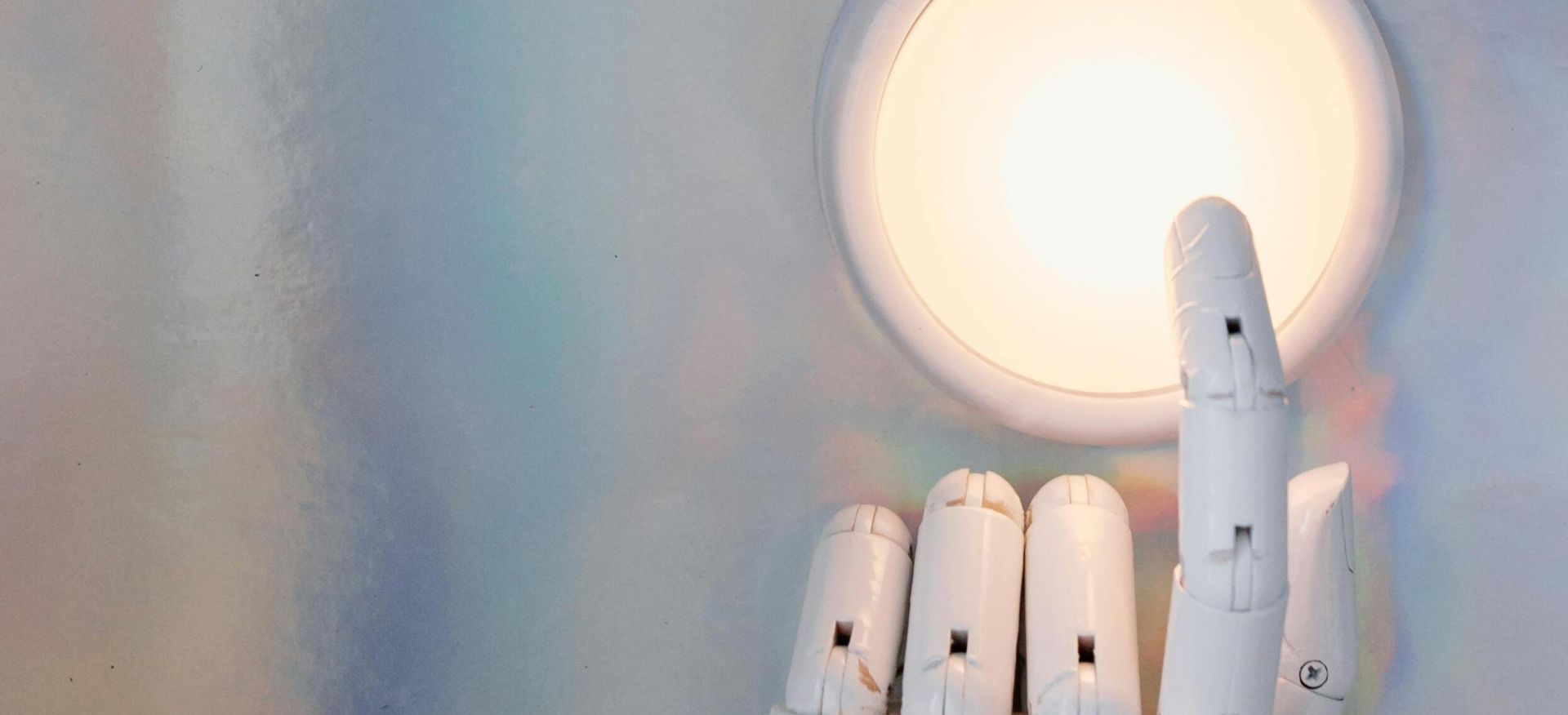 A robotic hand reaching towards a glowing circle on a pastel abstract background, hinting at advanced technology.