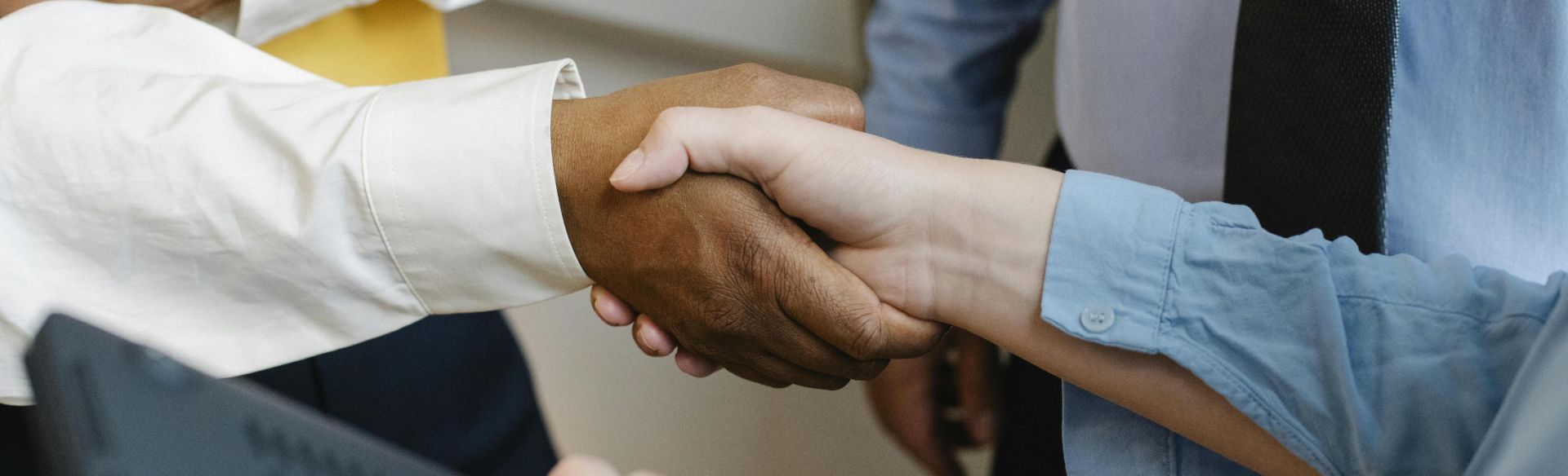 Crop anonymous diverse entrepreneurs shaking hands after meeting and negotiating about new project