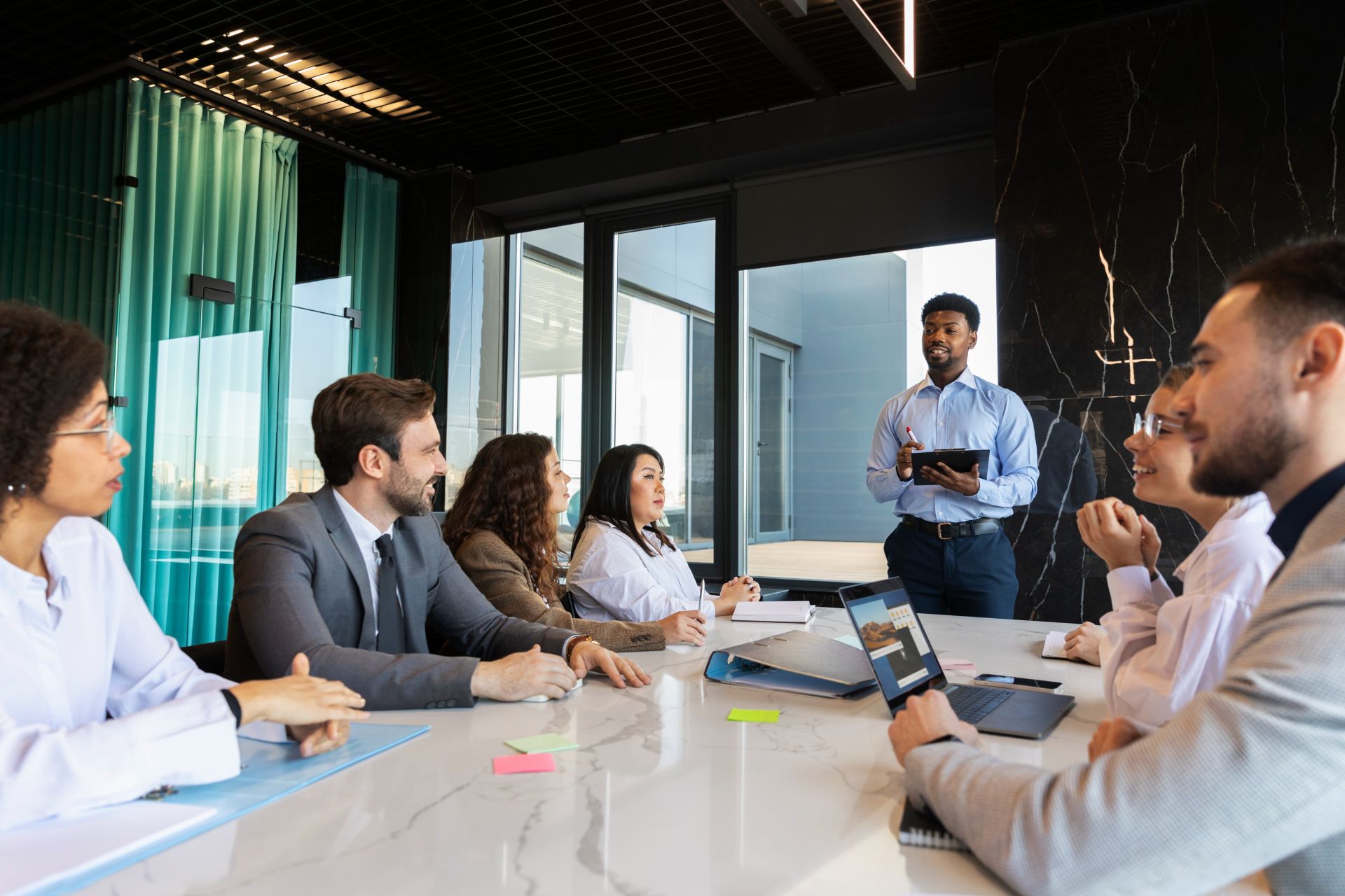 Three diverse professionals working and smiling at office desks, fostering teamwork and collaboration.